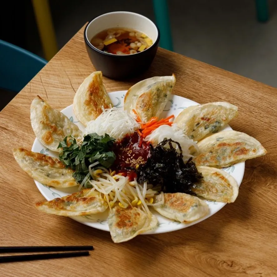 지우분식 비빔만두. 군만두 열 개를 접시에 둘러 담고 가운데 붉은 양념장·깻잎채·숙주·김·무채를 올렸다.