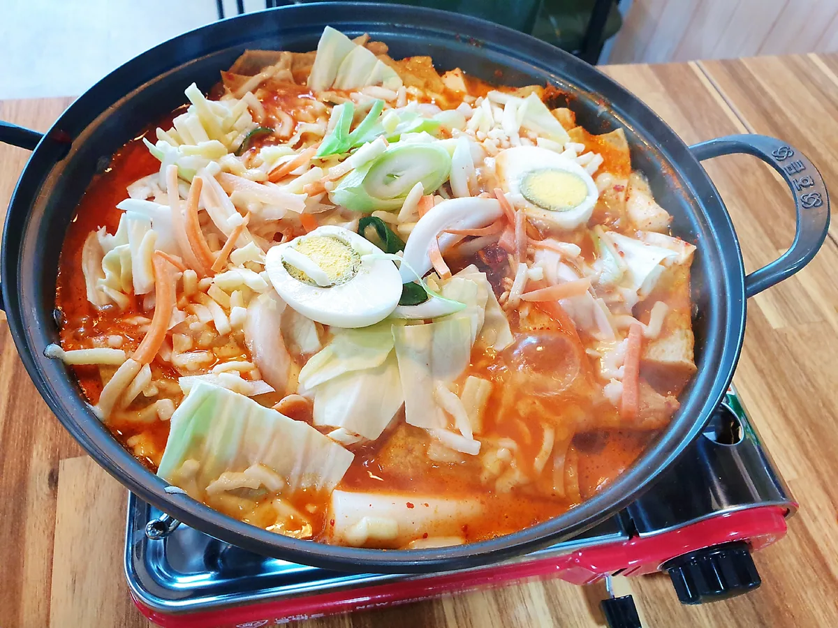 모래성분식포차 즉석떡볶이. 휴대용 가스레인지 위 냄비에 양배추, 당근, 삶은 달걀 반쪽 둘, 어묵, 떡, 대파가 끓는다. 값은 15,000원이다.