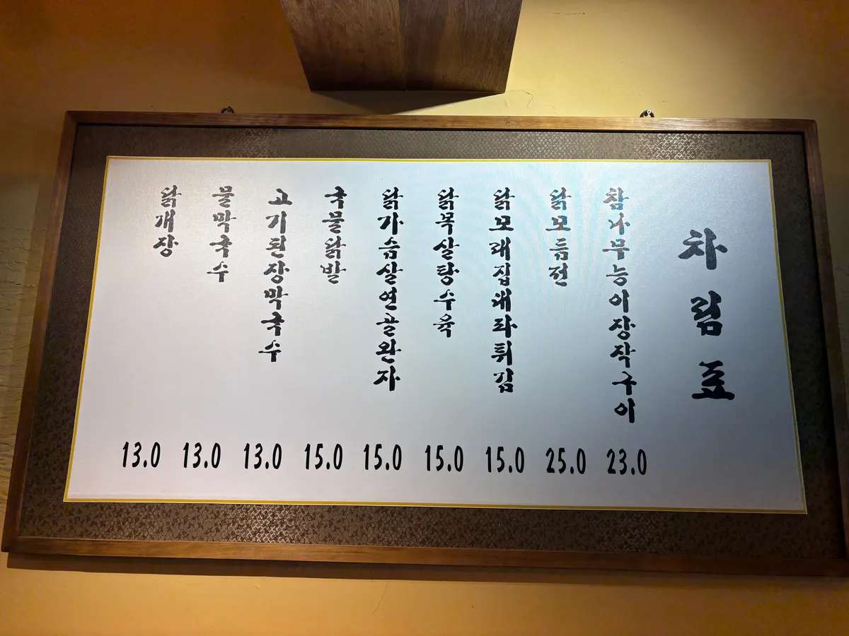 신당 계류관 차림표 액자. 세로쓰기로 아홉 줄이 적혀 있고 값은 천원 단위로 표시돼 있다.