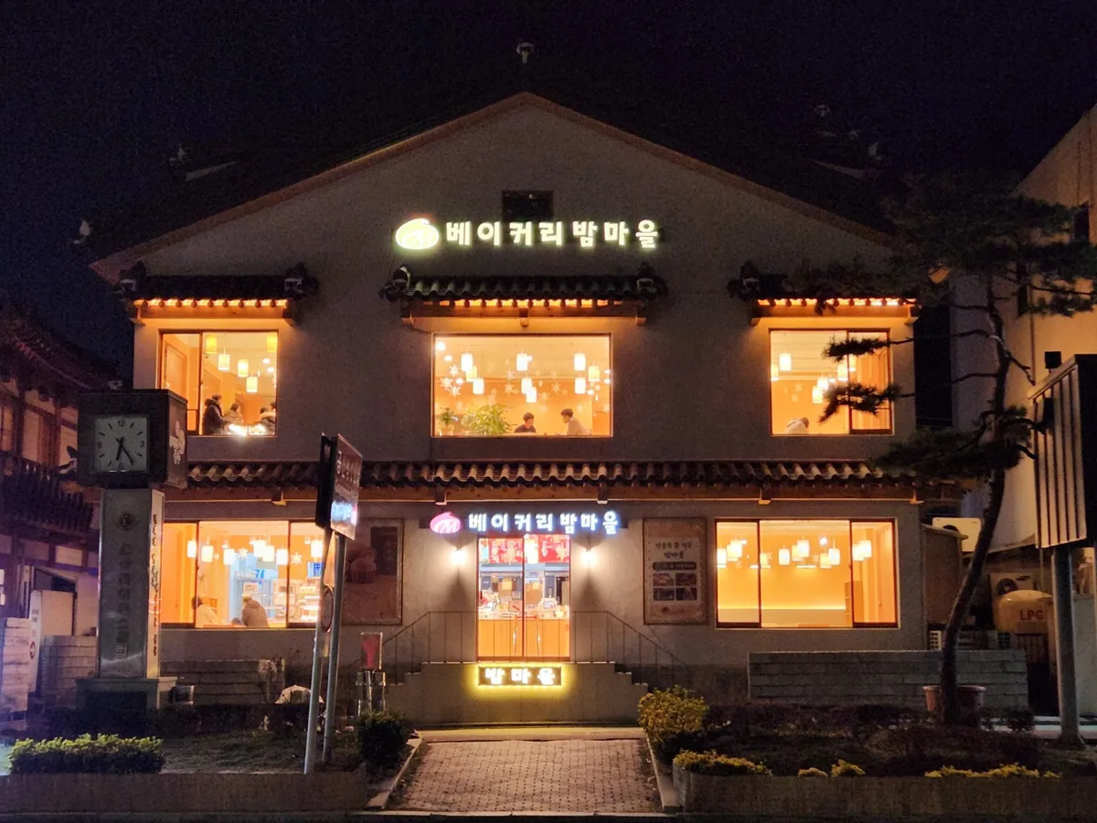 베이커리 밤마을 밤 외관. 2층 한옥 지붕, 박공 아래 간판에 불이 들어와 있다